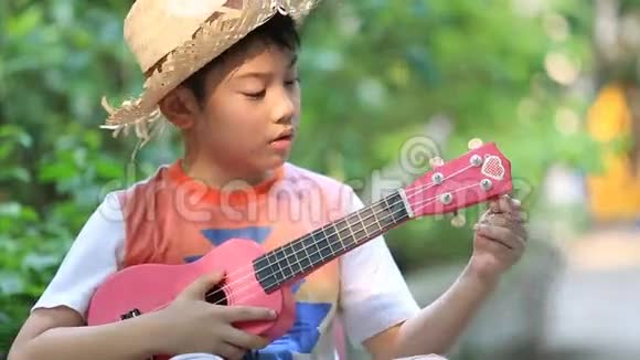 小亚洲小孩坐在迷你椅子上弹吉他视频的预览图