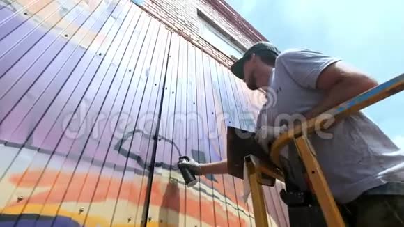 低景一位年轻的男性艺术家在墙上画一罐涂鸦颜料它应该在建筑塔上一个男人视频的预览图