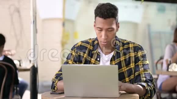 年轻的非洲男人在笔记本电脑户外咖啡馆视频的预览图