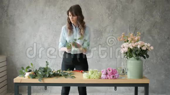 工作中的花商年轻漂亮的金发女郎用不同的花豌豆和玫瑰做时尚的现代花束视频的预览图