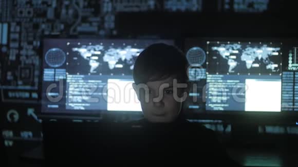 年轻的天才黑客程序员在数据中心的电脑上工作里面装满了显示屏肖像视频的预览图