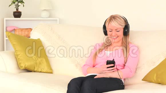 金发女人带着耳机听音乐视频的预览图