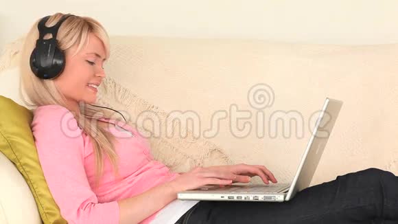 有魅力的女人在笔记本电脑上听音乐和冲浪视频的预览图