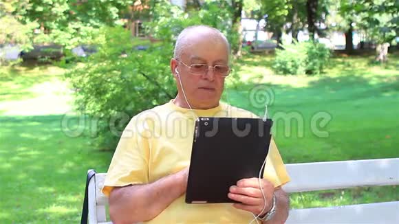一位老人在他的数码平板电脑上欣赏音乐视频的预览图