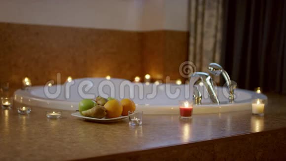 带水果的盘子站在浴室的按摩浴缸附近视频的预览图