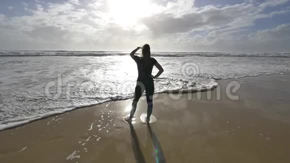 清晨美丽的年轻女性慢跑者在海滩上看太阳和海浪视频的预览图