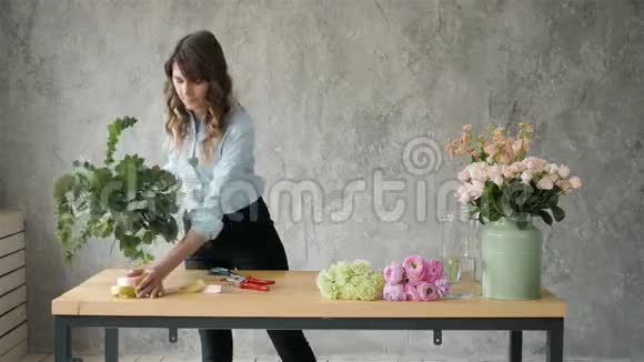 工作中的花商年轻漂亮的金发女郎用不同的花豌豆和玫瑰做时尚的现代花束视频的预览图