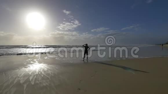 清晨美丽的年轻女性慢跑者在海滩上看太阳和海浪视频的预览图