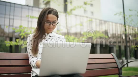 女孩看着笔记本电脑屏幕在键盘上打字视频的预览图