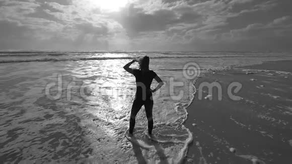 清晨美丽的年轻女性慢跑者在海滩上看太阳和海浪视频的预览图