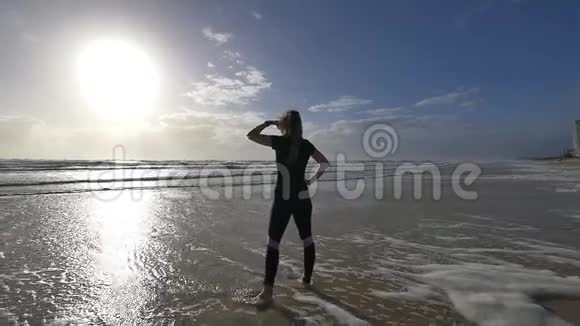 清晨美丽的年轻女性慢跑者在海滩上看太阳和海浪视频的预览图