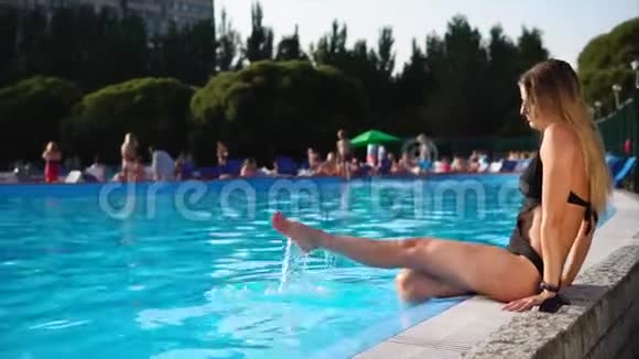 美丽的年轻女子坐在游泳池旁视频的预览图