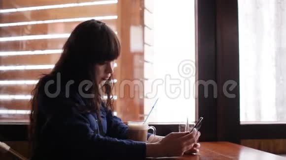 小女孩在咖啡馆的智能手机上自拍视频的预览图