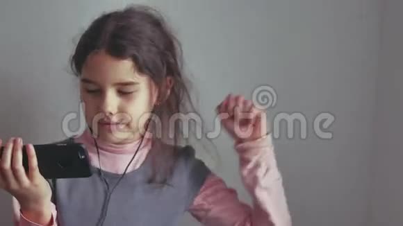少女听着音乐耳机在智能手机上跳舞视频的预览图