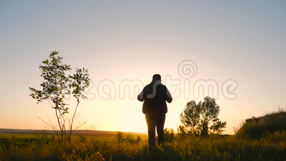 一个背着背包的男人在明亮的天空日落时的剪影太阳下山了旅行概念旅游旅行性质视频的预览图