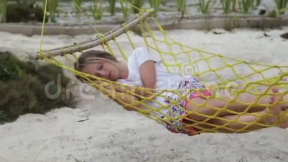 年轻女孩在海边的吊床上放松视频的预览图