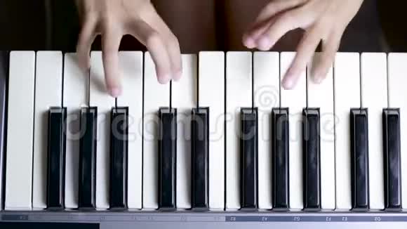 特写镜头中钢琴钥匙的手孩子学弹钢琴视频的预览图