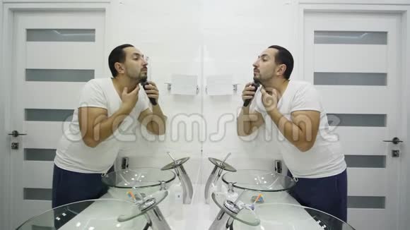 年轻人在浴室用电动剃须刀刮胡子视频的预览图