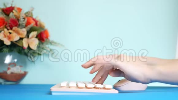 特写镜头时尚的问候视频卡雌性的手在粉红色的键盘上打字旁边是一朵花在蓝色上视频的预览图