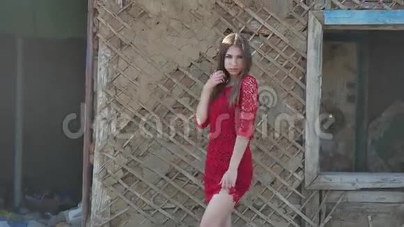 穿红色裙子的漂亮女孩穿裙子的女孩站在废墟的旧房子旁边生活方式视频的预览图