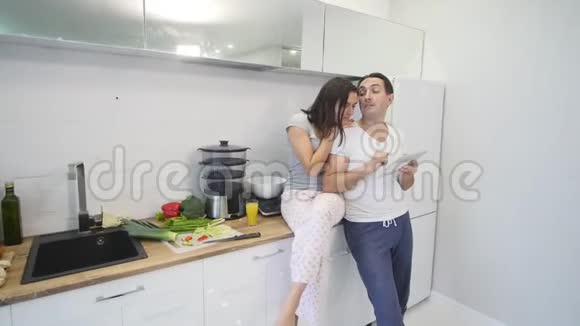 家庭厨房里有平板电脑的幸福夫妻视频的预览图