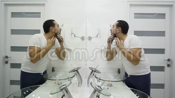 年轻人在浴室用电动剃须刀刮胡子视频的预览图