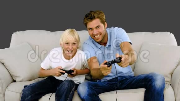 父亲和儿子在灰色背景的沙发上玩电子游戏视频的预览图