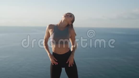 清晨在悬崖上做运动的女孩看着海洋慢动作视频的预览图