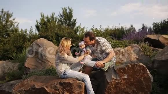 日落时带着女儿在公园玩耍的年轻父母视频的预览图
