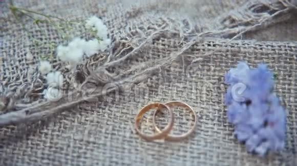 结婚戒指和亚麻背景上的花视频的预览图