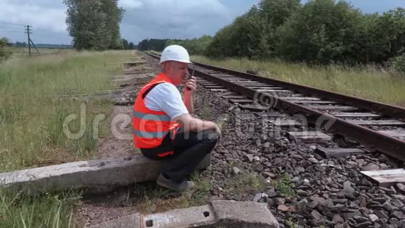 坐在铁轨旁的对讲机里的铁路工人视频的预览图
