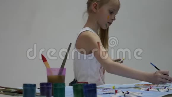 可爱的小女孩画家在桌子上画画在她的衣服上画画慢动作视频的预览图