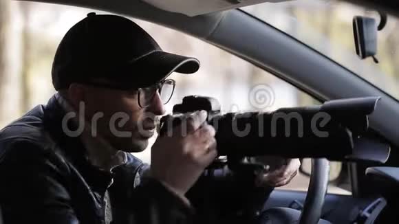 私家侦探坐在车里用数码相机拍照视频的预览图