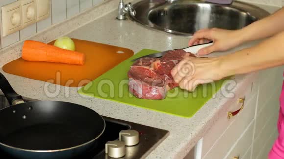 女性手在切割板上切割生肉在厨房准备晚餐视频的预览图