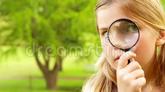 可爱的小女孩在公园里用放大镜视频的预览图