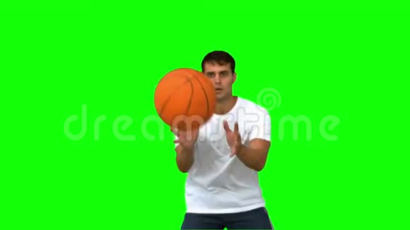 一个英俊的男人在绿色的屏幕上接球和投掷篮球视频的预览图