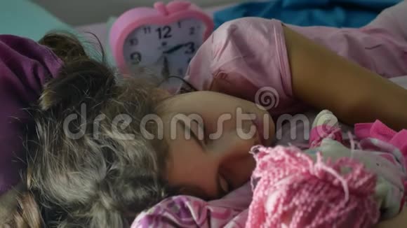 可爱的小女孩晚上睡在沙发床上拥抱她的室内娃娃女孩深肤色的少年可爱的睡着了视频的预览图