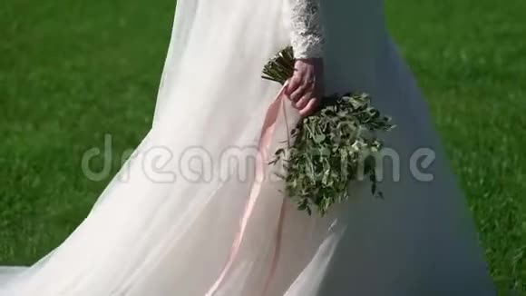 穿着婚纱的年轻新娘在公园里散步白色豪华礼服视频的预览图