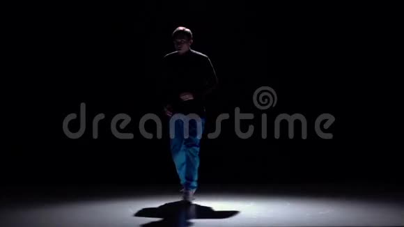 穿着蓝色裤子跳舞的现代男子黑色阴影慢动作视频的预览图