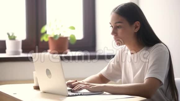 使用笔记本电脑的年轻女子在办公桌上打电话视频的预览图