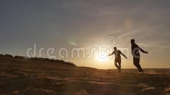 跑步者两个男人在沙滩上奔跑在沙滩上运动傍晚日落太阳赛跑者视频的预览图