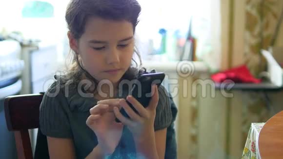 女孩早餐在厨房玩智能手机社交媒体在线游戏视频的预览图