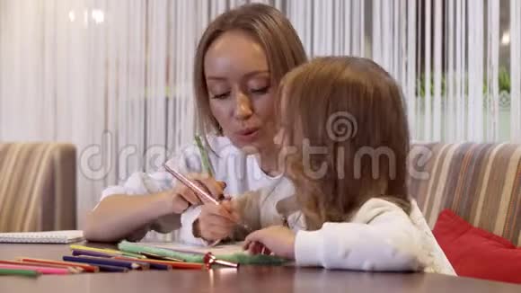 积极的年轻女子和她美丽的小女儿一起画画视频的预览图