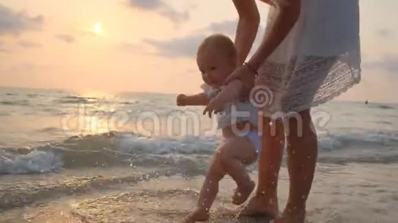 夕阳西下年轻美丽的女人带着她的小宝宝在海滨散步视频的预览图