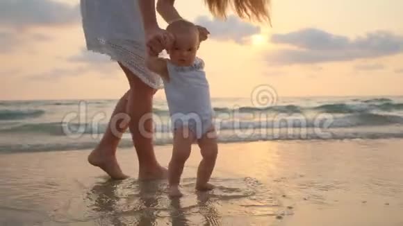 夕阳西下年轻美丽的女人带着她的小宝宝在海滨散步视频的预览图