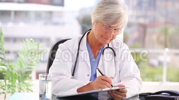 严重成熟的医生在剪贴板上写字视频的预览图
