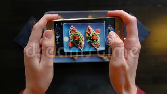 女手在餐厅用智能手机拍摄开胃的食物视频的预览图