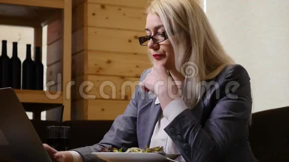 女商人在咖啡馆里吃午饭用笔记本电脑工作视频的预览图