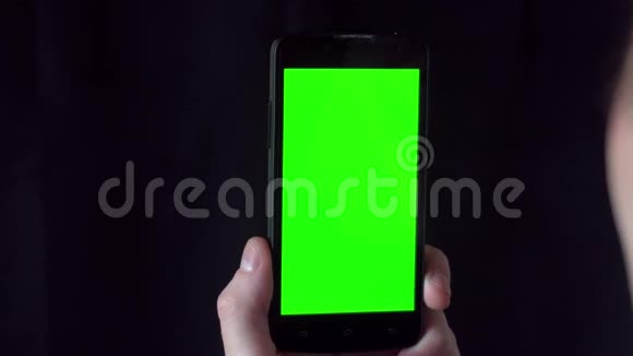 穿着衬衫的年轻人拿着手机面前有绿色屏幕视频的预览图