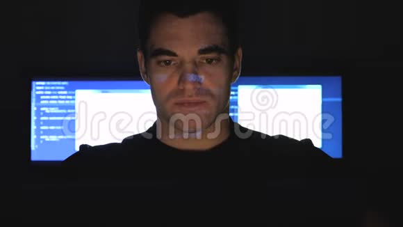 开发者黑客程序员在数据中心的电脑上工作而蓝码字符在他的脸上反射视频的预览图